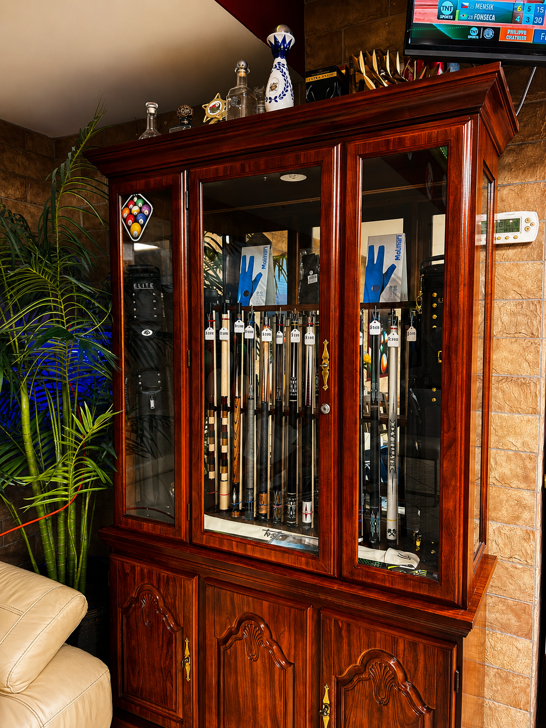 Cue sticks, gloves, carrying bags, and accessories displayed in the Gentlemen's Cue Club pro shop cabinet